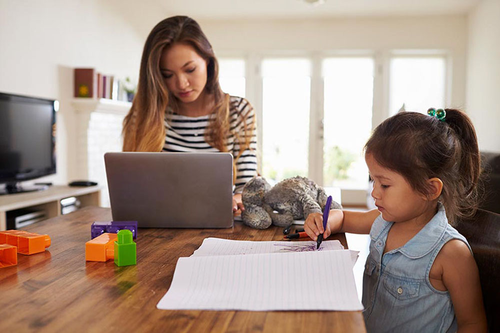 SIS Mother works on laptop as daughter draws picture